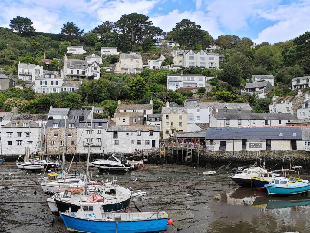 An image of polperro sky there are white clouds in the sky and the tide is out